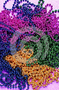 Carnival shiny beads, traditional carnaval accessories. Mardi gras frame or border on purple background, masquerade masks and