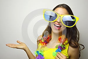 Carnival time. Young woman with big funny sunglasses and carnival garland smile at camera and show your product or text