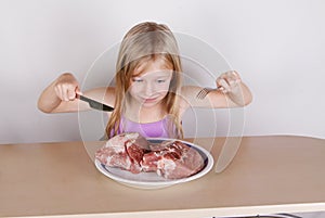 Carnivore keto diet concept - little blond girl eating raw meat