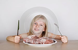 Carnivore keto diet concept - little blond girl eating raw meat