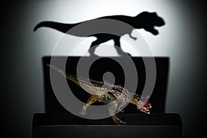 A carnotaurus casting a tyrannosaurus shadow in dark concept of strength & aspirations