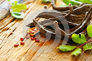 Carob. Healthy organic sweet carob pods with seeds and leaves on a wooden table. Healthy eating