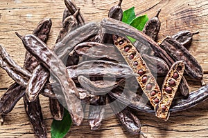 Carob pods and carob beans on the wooden table