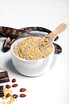 Carob pods and carob powder over white background