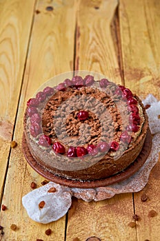 Carob tart with cherries ans raisins on the wooden background. Powdered carob pie with cherries