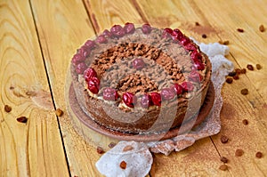 Carob tart with cherries ans raisins on the wooden background. Powdered carob pie with cherries