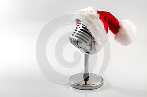 Carols and Christmas music concept with a microphone wearing a santa hat isolated on white with copy space