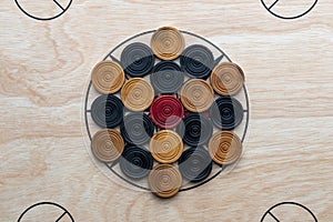 Carom board with striker, carom men, and queen.