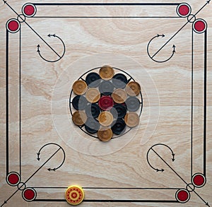 Carom board with striker, carom men, and queen.