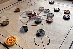 Carom board with striker, carom men, and queen.