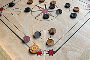 Carom board with striker, carom men, and queen.