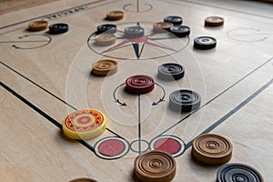 Carom board with striker, carom men, and queen.