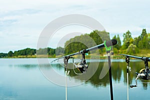 Carp fishing on beautiful blue lake with carp rods and rod pods in the summer morning. Fishing from the wooden platform.