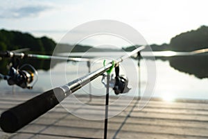 Carp fishing on beautiful blue lake with carp rods and rod pods in the summer morning. Fishing from the wooden platform