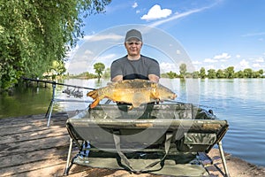 Carp fishing. Fisherman with fish trophy in hands at lake