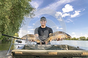 Carp fishing. Fisherman with fish trophy in hands at lake