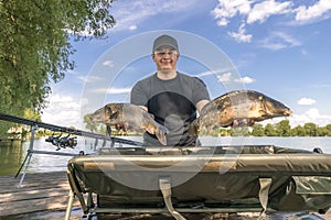 Carp fishing. Fisherman with fish trophy in hands at lake