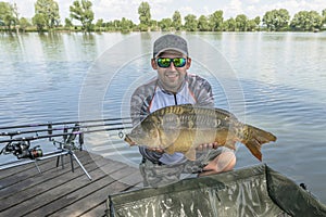 Carp fishing. Fisherman with fish trophy in hands at lake