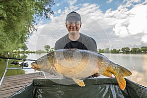 Carp fishing. Fisherman with fish trophy in hands at lake