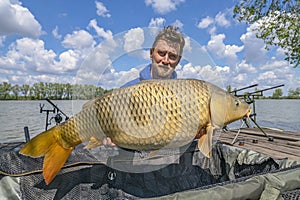 Carp fishing. Fisherman with fish trophy in hands at lake