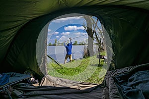 Carp fishing. Fisherman make a cast. View from tent
