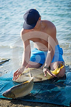 Carp fishing. Young fisherman catching a big common carps that slipped from his hands. Close up portrait.