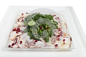Carpaccio octopus with shpinach in a white plate