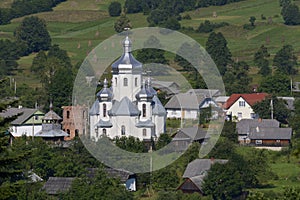 Carpathian village: catholic church, country houses, gardens and hill