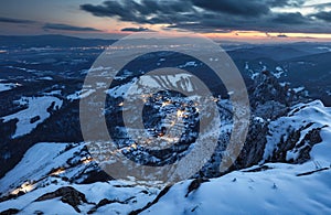 Carpathian winter mountain village in light with wooden houses on a hill covered with fresh snow