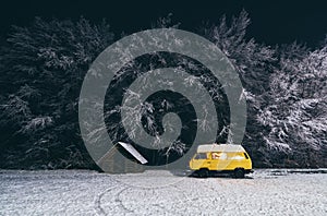 Carpathians, Ukraine - December 2019: yellow camper van with winter forest on background