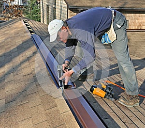 Carpenter applying caulk to ridge vent