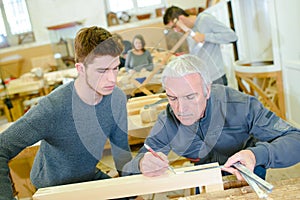 Carpenter and apprentice installing fitted kitchen