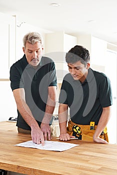Carpenter And Apprentice Installing Luxury Fitted Kitchen