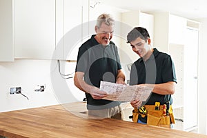Carpenter And Apprentice Installing Luxury Fitted Kitchen