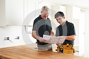 Carpenter And Apprentice Installing Luxury Fitted Kitchen photo
