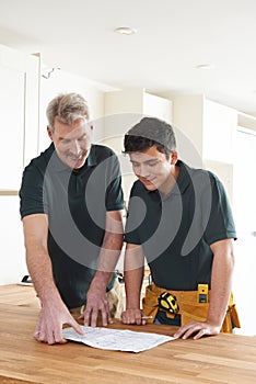 Carpenter And Apprentice Installing Luxury Fitted Kitchen