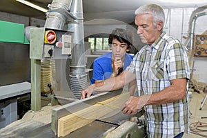 Carpenter with apprentice measuring wood