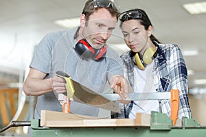 carpenter and apprentice working together in wood workshop