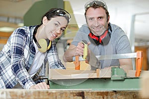 carpenter and apprentice working together in wood workshop