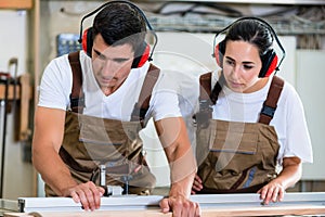 Carpenter and apprentice working together in workshop