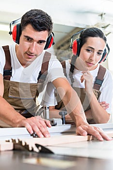 Carpenter and apprentice working together in workshop