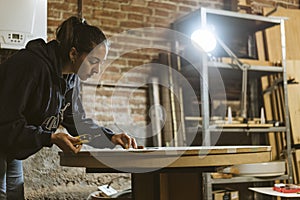 Carpenter / Artisan girl is concentrated working on an old wood table in her workshop. Woman restores an antique furniture