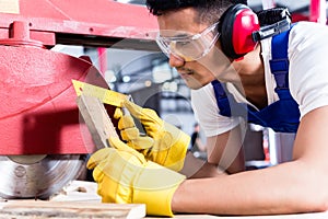 Carpenter in Asian workshop with circular saw