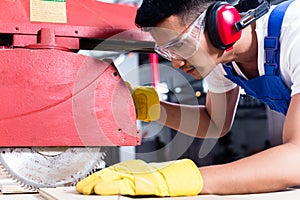 Carpenter in Asian workshop with circular saw