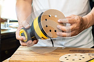 Carpenter attach sandpaper to an orbital sander or palm sander after remove the paper backing of the sandpaper.DIY maker and