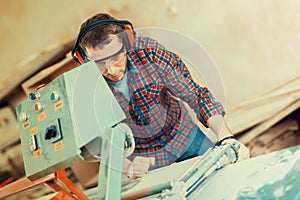 Carpenter with automatic circular saw. He has protective glasses