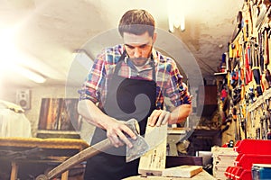 Carpenter with ax and board working at workshop