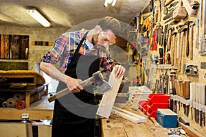 Carpenter with ax and board working at workshop