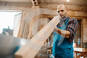 Carpenter with board near plane machine, carpentry