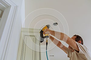 Carpenter brad using nail gun to Crown Moulding on kitchen cabinets framing trim,